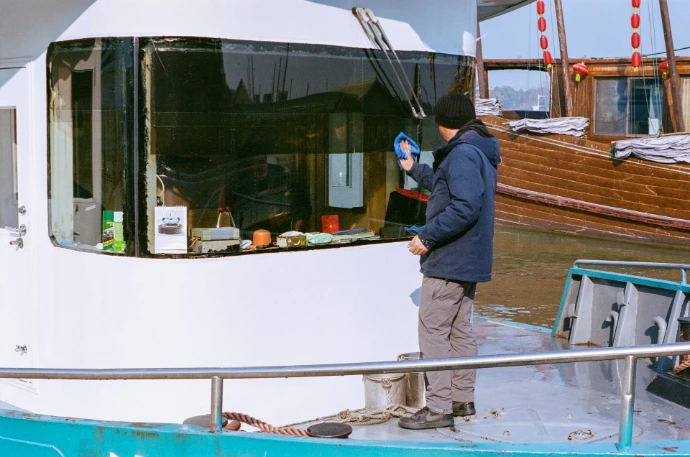 Hombre limpia la ventana de un barco.